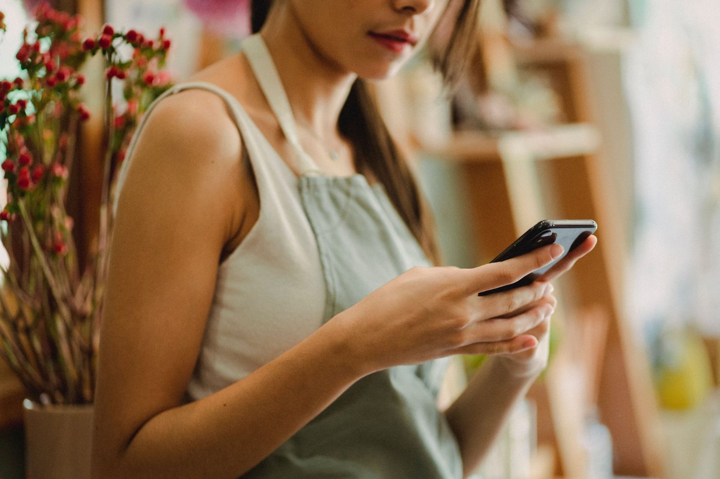 Titolare di un negozio di fiori che legge un messaggio sullo smartphone