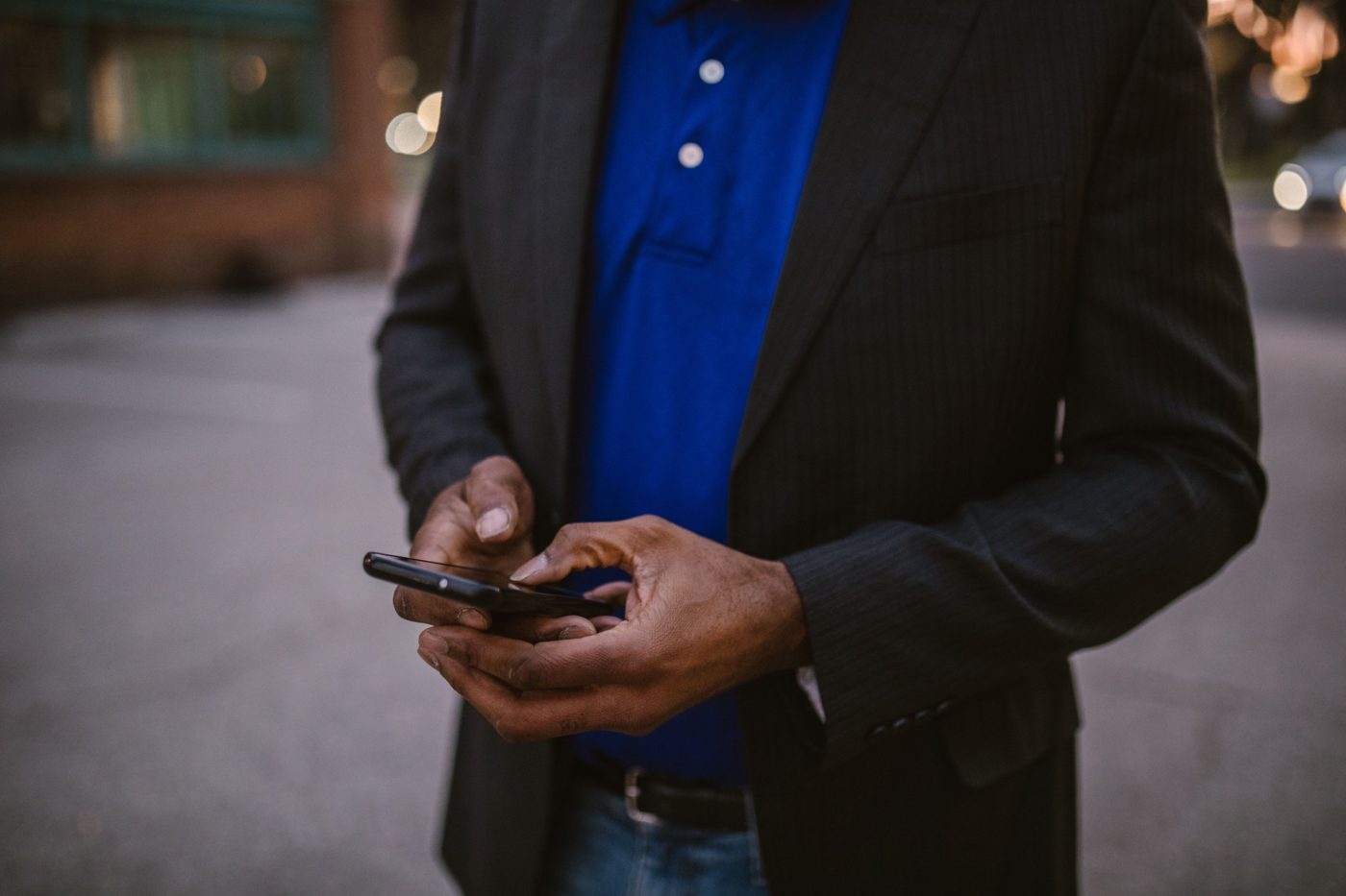 Uomo in giacca che usa lo smartphone per strada