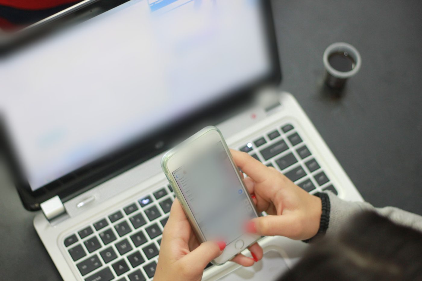 Persona che usa lo smartphone davanti al portatile